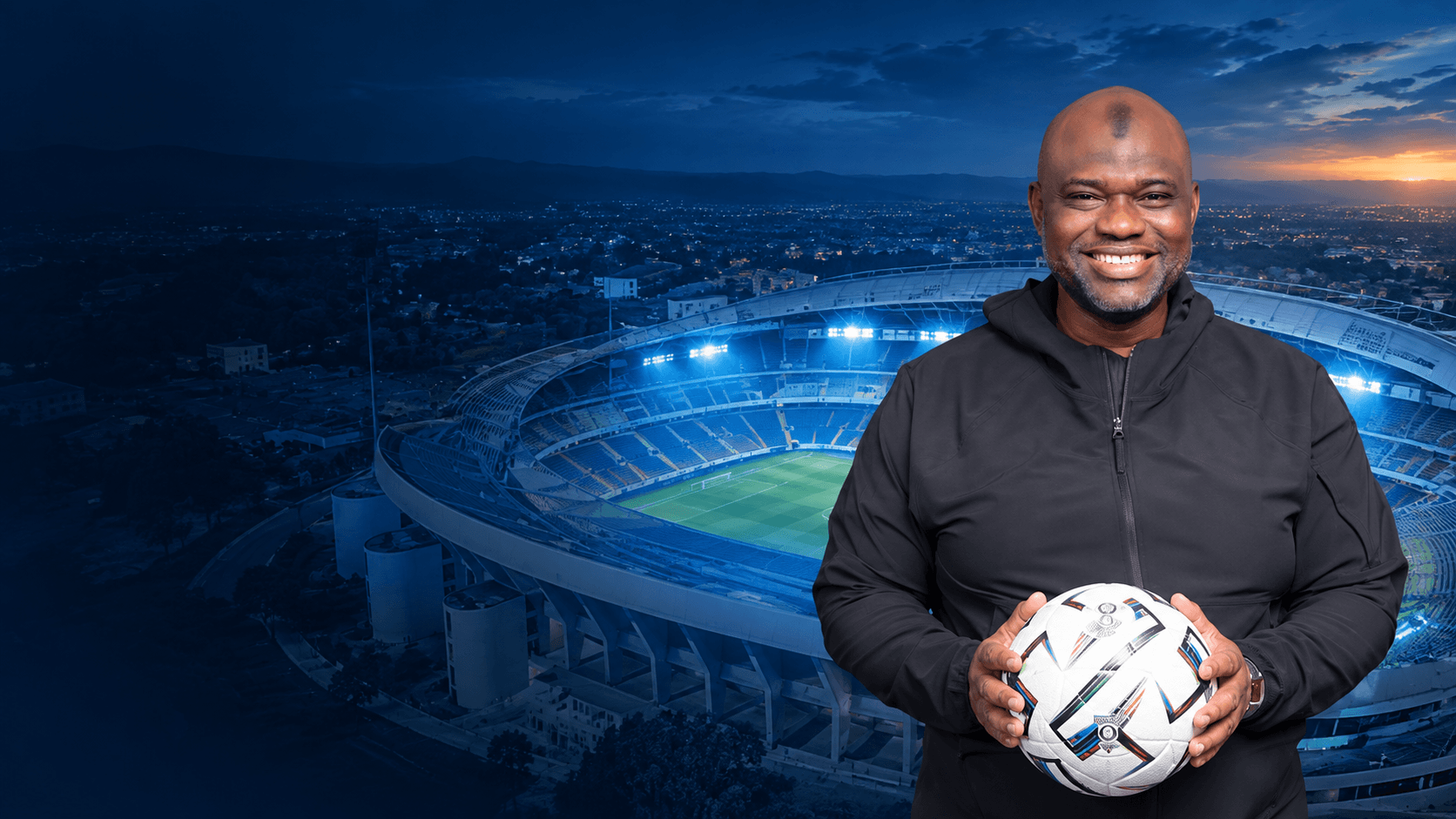 Bachir Haïdara Chérif souriant, un ballon de football dans les mains, devant un grand stade éclairé de nuit